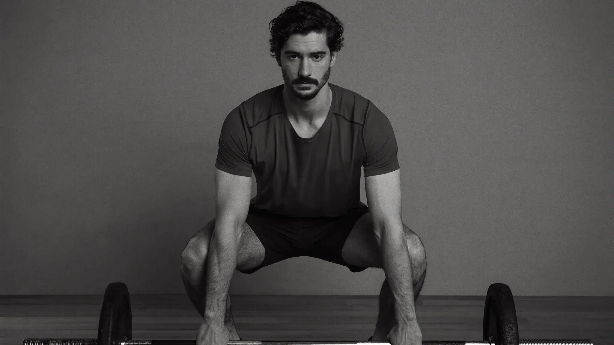 Young man performing a bodyweight squat in a home gym space — beginner strength training for Christians