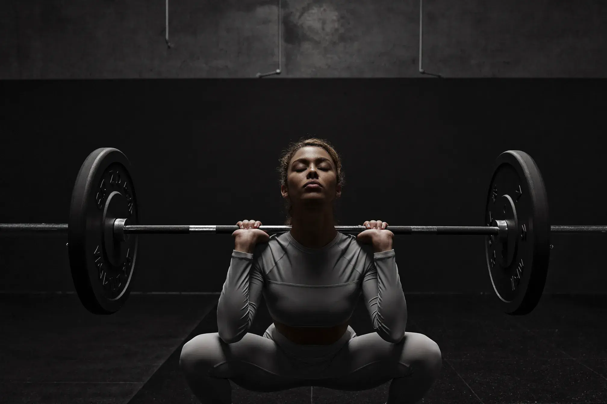 Christian woman performing a barbell back squat in a clean gym setting - faith-based strength training