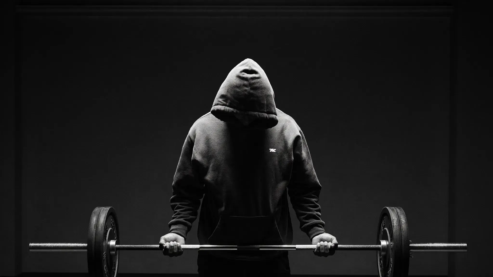 Lifter bowing head at the barbell before a heavy set - training as worship and devotion