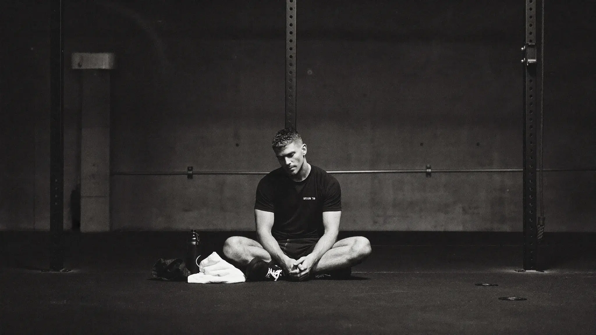 Athlete seated quietly after a training session, head bowed, towel around neck - training as worship completed