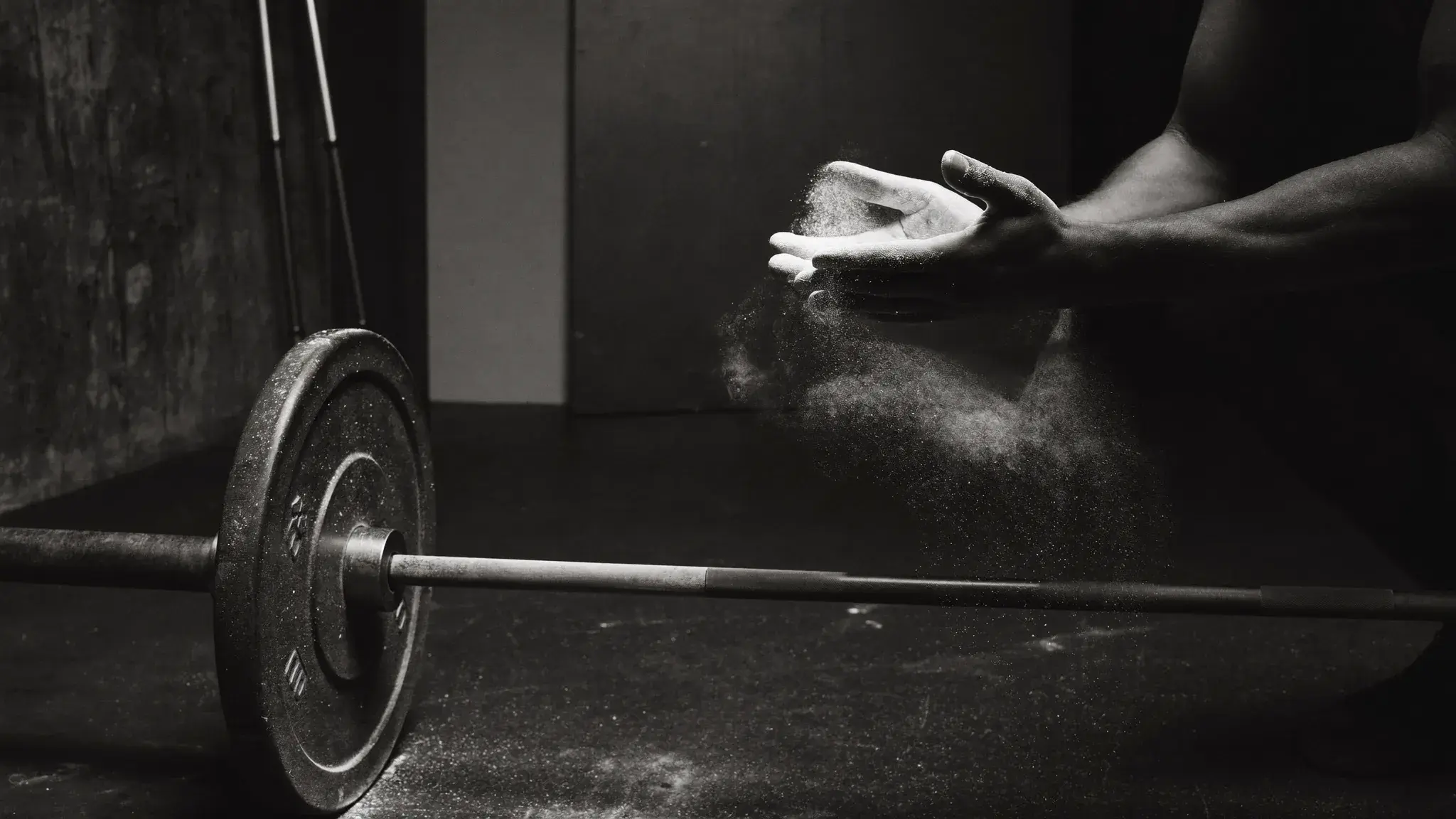 Athlete chalking hands before a heavy barbell set - deliberate preparation as a ritual of long-term endurance training