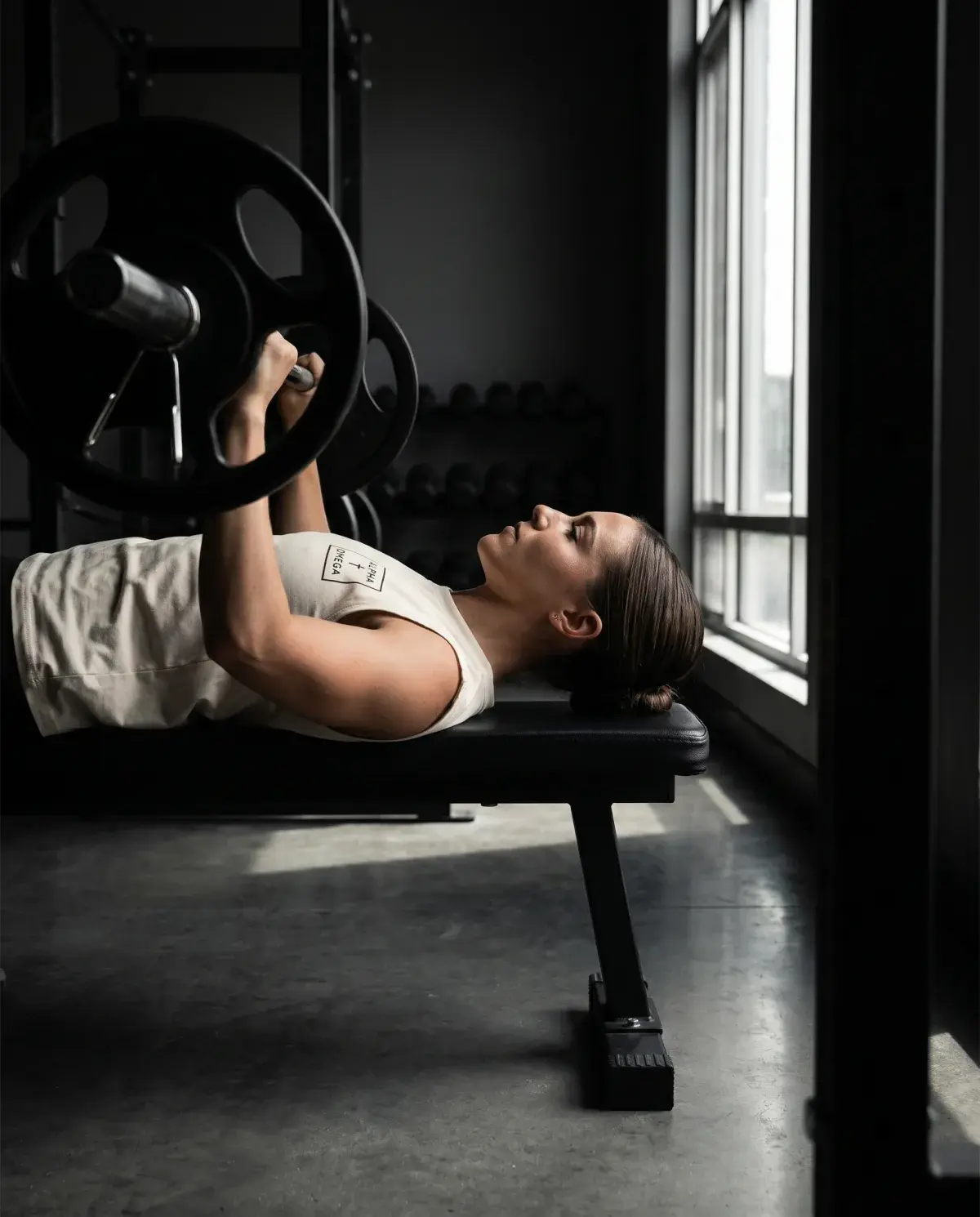 Athlete on the bench press in the cream Alpha Omega gear