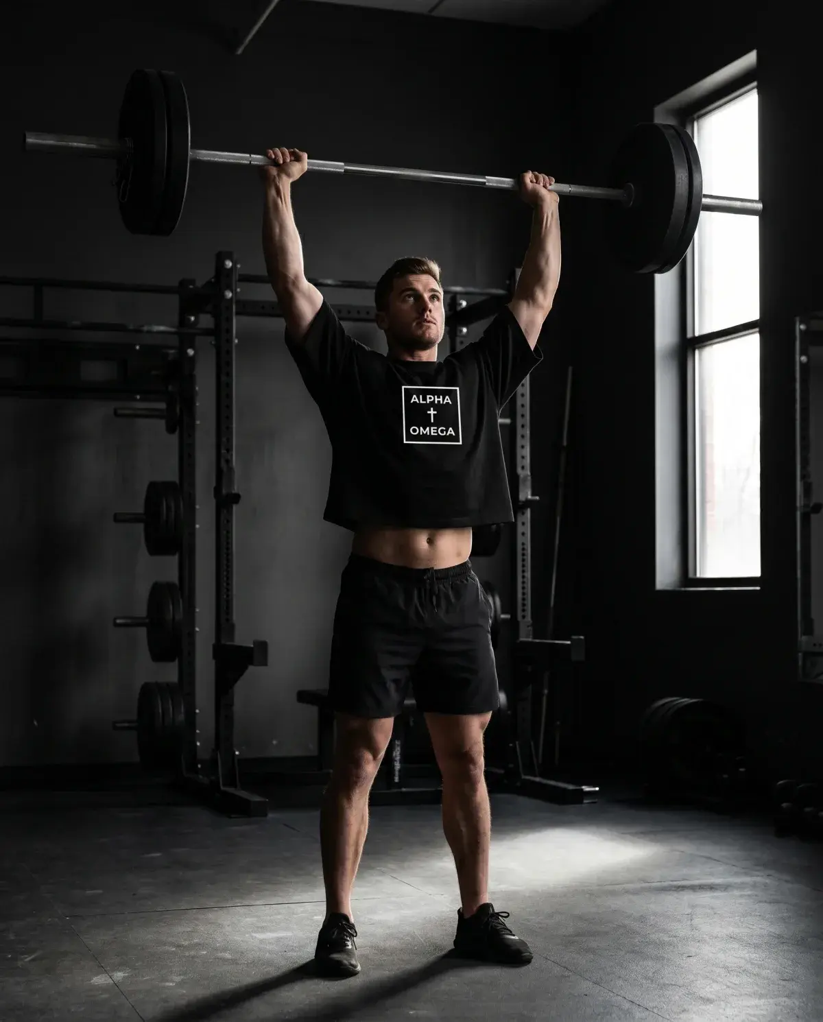Athlete pressing overhead in the black Alpha Omega gear