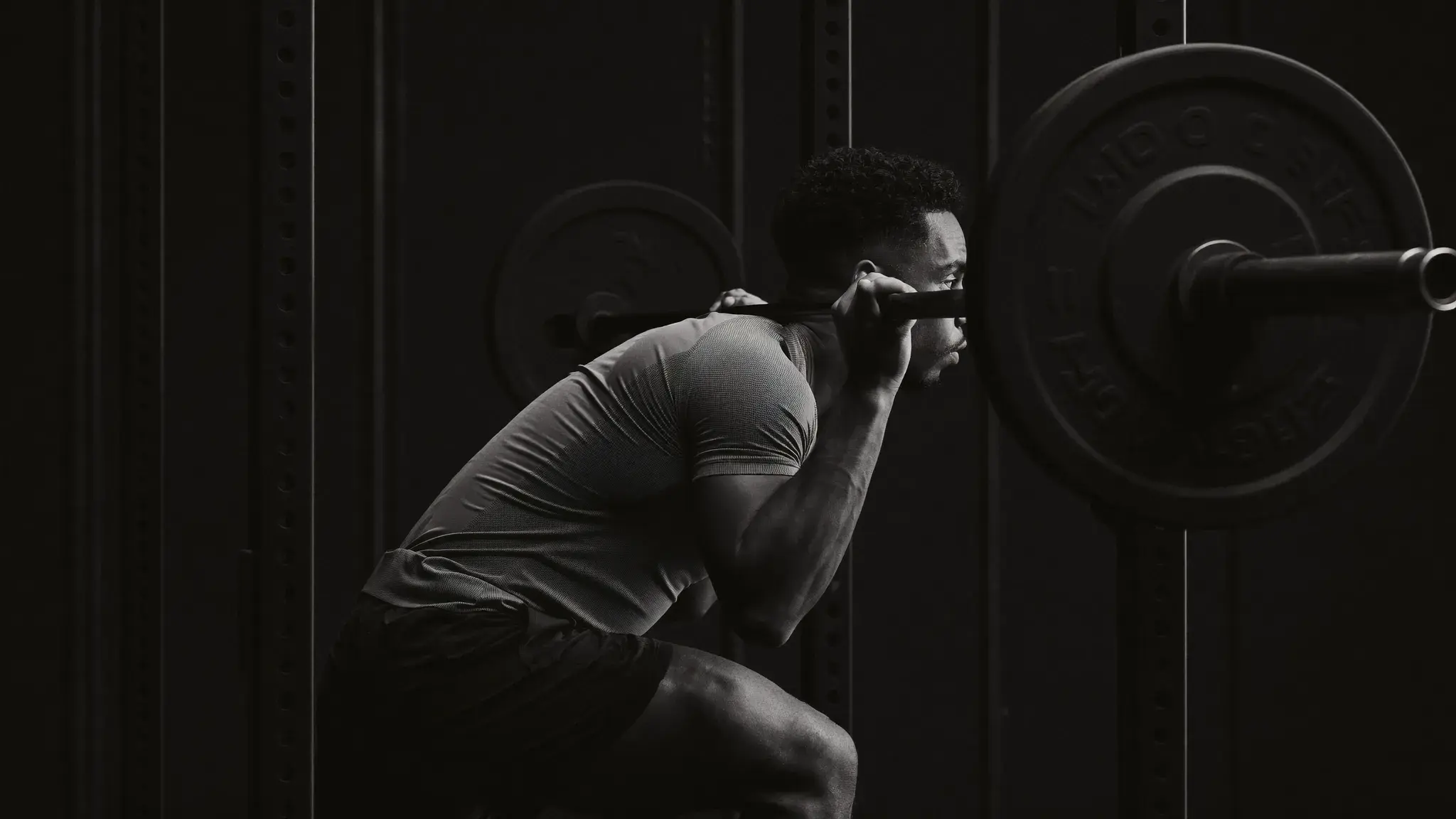 Lifter preparing for a heavy squat under a loaded barbell in a quiet gym - intermediate progressive overload training